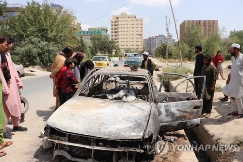 30일(현지시간) 아프가니스탄인들이 수도 카불 국제공항에 로켓포 공격을 가하다 파괴된 차량을 살펴보고 있다. 이날 카불 공항에는 5발의 로켓포탄이 날아들었으나 미군 방어시스템에 의해 차단됐다.  [카불=AP 연합뉴스]